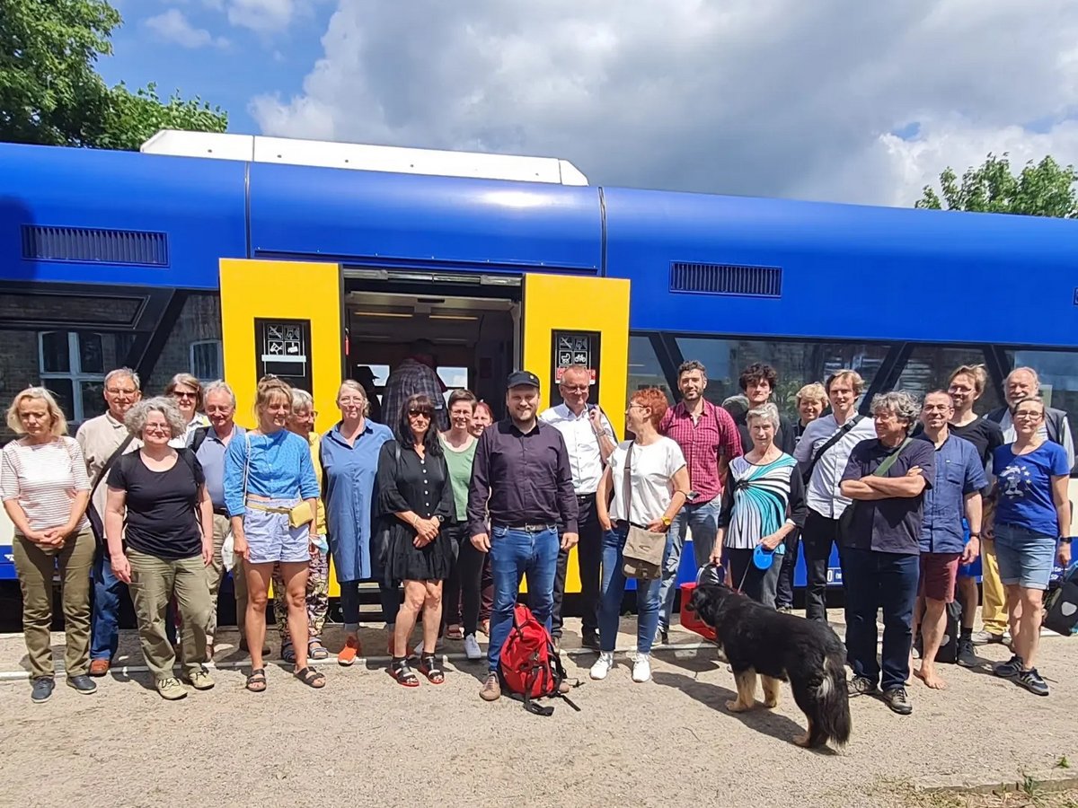 Befürworter*innen der Fortsetzung des Probebetriebs am Bahnhof Joachimsthal vor einem haltenden Zug.